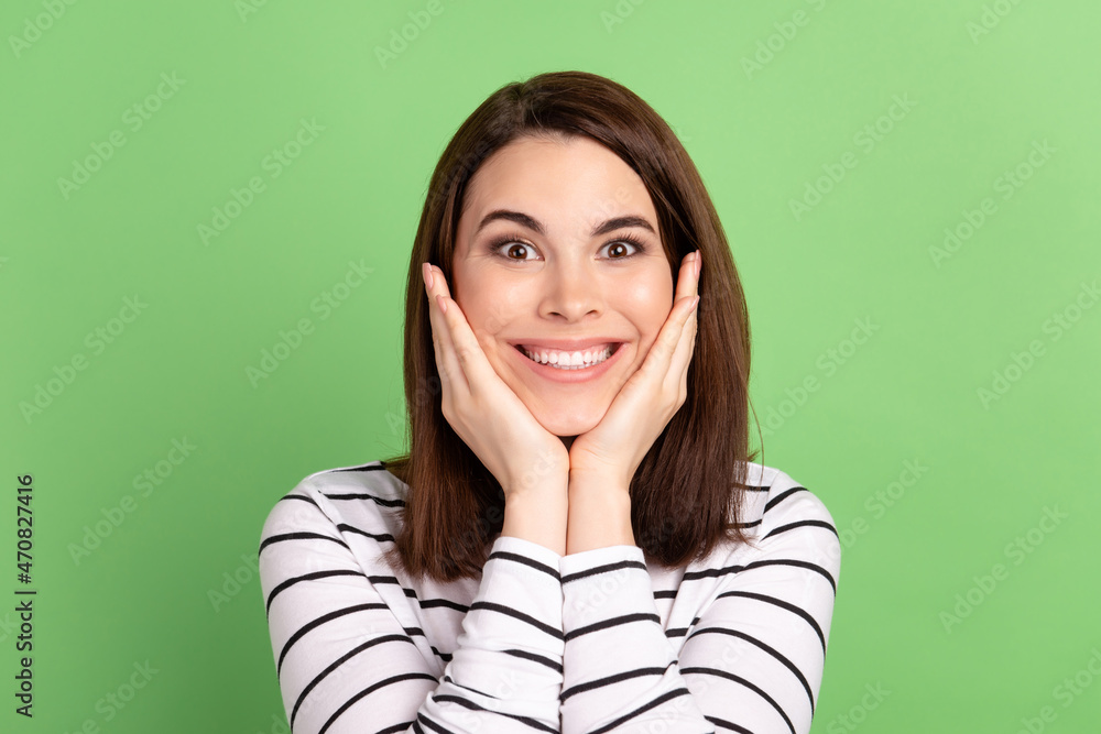 Photo of young cheerful girl arms touch cheek good mood flawless isolated over green color background Photo of young cheerful girl arms touch cheek good mood flawless isolated over green color background