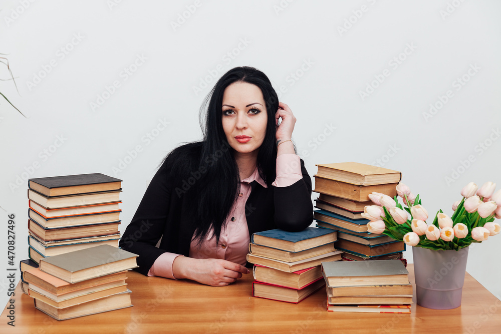 beautiful brunette woman in a business suit learns to read books at the table beautiful brunette woman in a business suit learns to read books at the table