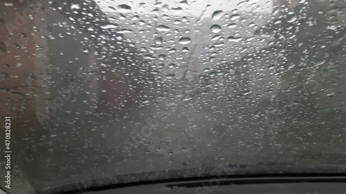 Car windshield covered with flowing drops of water during sleet photo