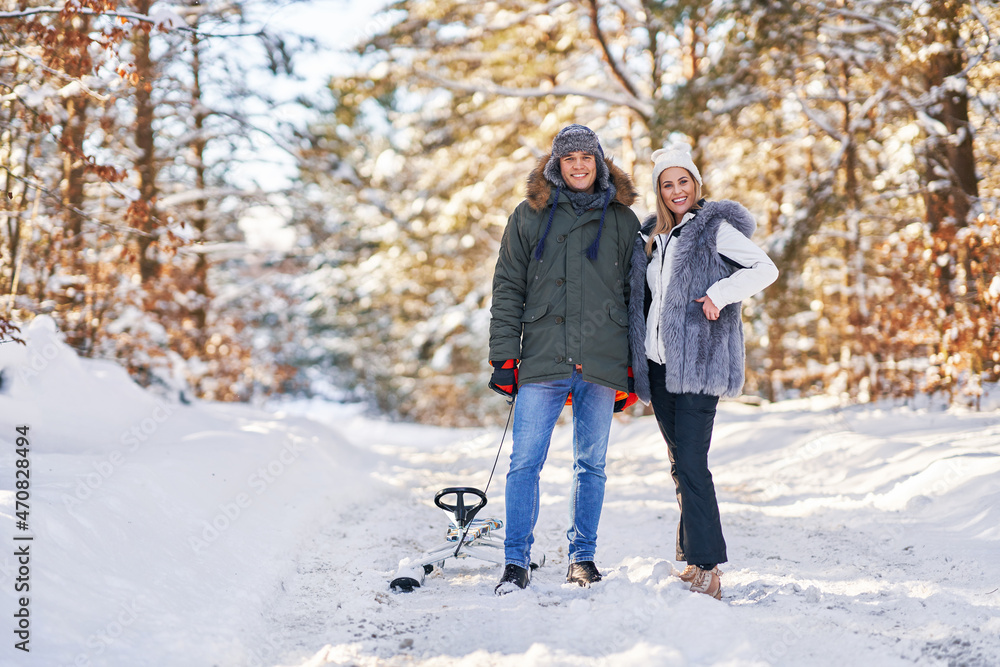 Couple having fun with sledge on snow in winter Couple having fun with sledge on snow in winter