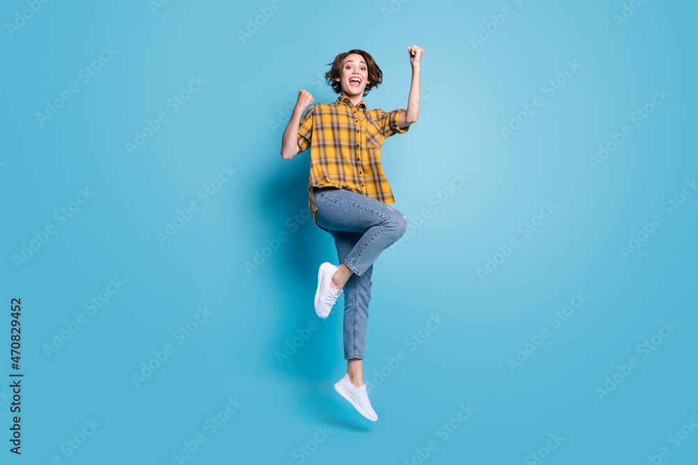 Photo of cheerful lady jump gain achievement wear plaid shirt jeans shoes isolated blue color background