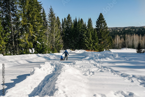 Man rolls child on snowmobile in park. © Татьяна Максимова