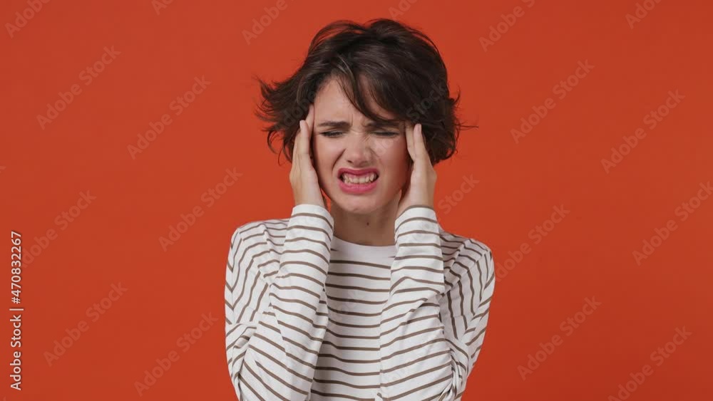 Sick ill young brunette woman 20s years old wears striped shirt put hands on head rub temples having headache suffering from migraine feel bad seedy isolated on plain orange background studio portrait Sick ill young brunette woman 20s years old wears striped shirt put hands on head rub temples having headache suffering from migraine feel bad seedy isolated on plain orange background studio portrait