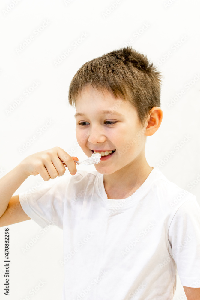 A boy in a white T-shirt is brushing his teeth in the bathroom. A boy in a white T-shirt is brushing his teeth in the bathroom.