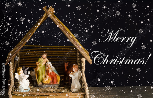 Christmas card with figures of Jesus, Virgin Mary and Joseph on a dark background with the inscription Merry Christmas.