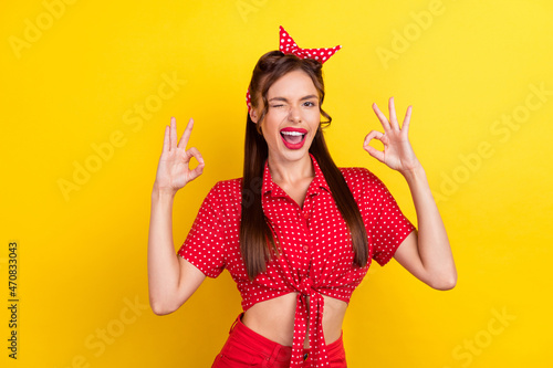 Photo of shiny sweet young lady wear dotted outfit showing okey signs winking smiling isolated yellow color background