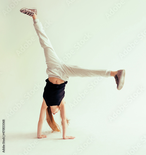 Canvas Print Attractive flexible teenage girl doing handstand on light background