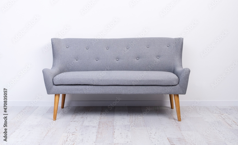 Gray couch standing on light laminate floor near white wall Gray couch standing on light laminate floor near white wall