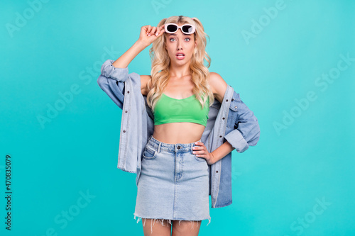 Photo of young unhappy upset young woman hold hand sunglass waist bad mood isolated on blue color background