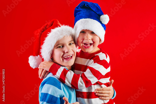 Two little toddler boy and girl in a Santa's hat for Christmas is isolated on a red background.Holidays concept.