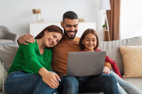 Happy Arab family using laptop in living room