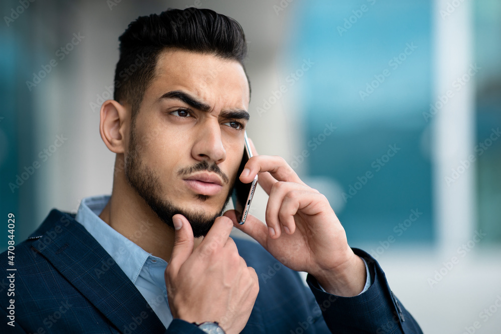 Confused middle eastern businessman having phone conversation, closeup portrait, panorama