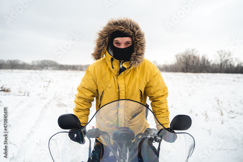 A man in a yellow jacket is driving a sports snowmobile