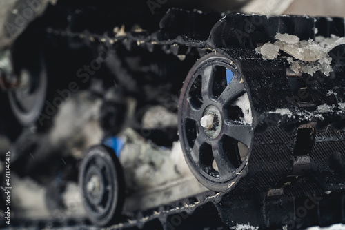 black rubber track of a snowmobile covered with chunks of ice