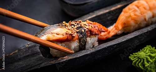 Sushi sashimi set with shrimps and wasabi served with wooden chopsticks on black taable. Traditional japanese meal with rice and seafood closeup photo