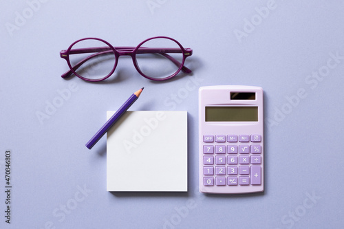 Obraz na płótnie Notepad, colored pencil, calculator, glasses on purple background. workspace. flat lay, top view w salonie