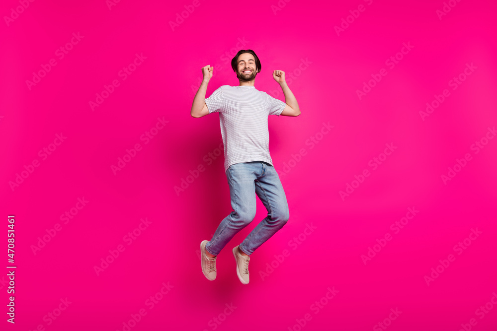 Photo of astonished triumphant guy jump rejoice win wear striped t-shirt jeans sneakers isolated pink color background Photo of astonished triumphant guy jump rejoice win wear striped t-shirt jeans sneakers isolated pink color background