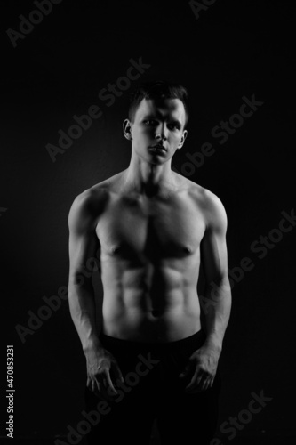 Black and white portrait of an athletic guy on a black background.