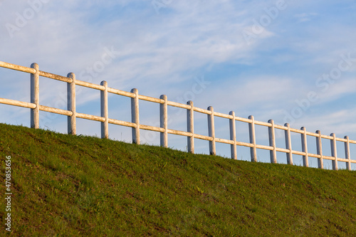White Wood Pole Fence Grass Embankment Blue Sky
