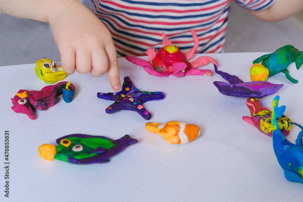Childs hands and crafts made of plasticine, preschooler sculpts from dough for sculpting figures of marine animals