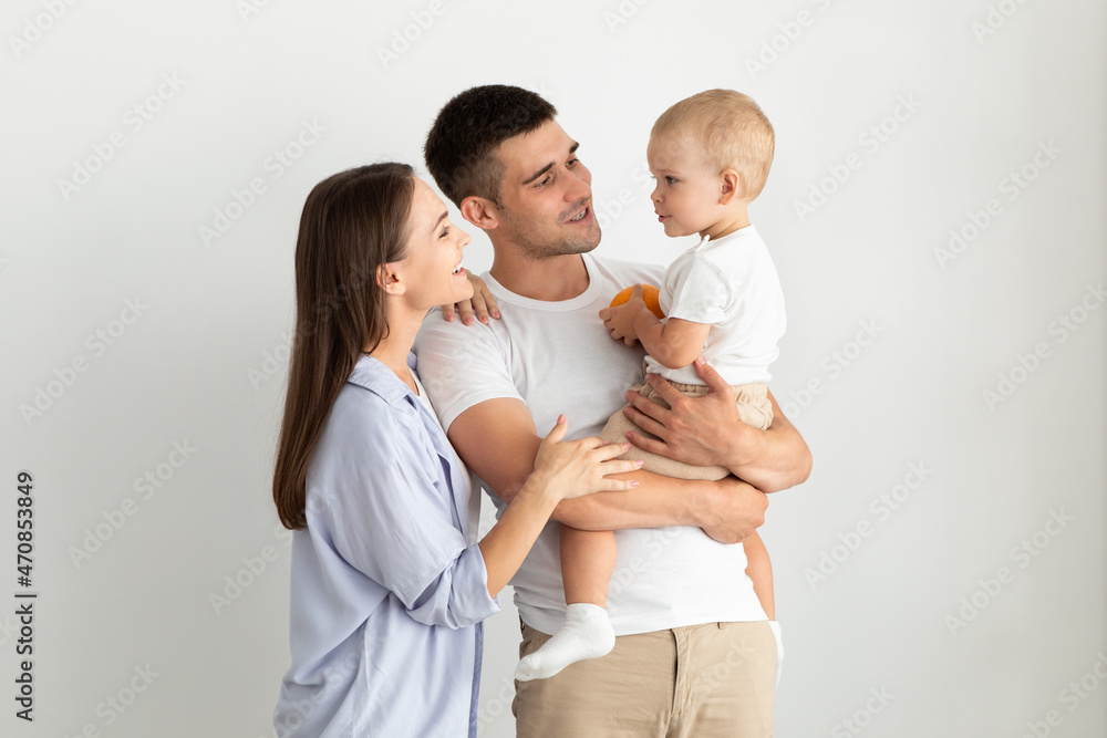 Parenthood Concept. Portrait Of Happy Young Parents Holding Their Cute Infant Child