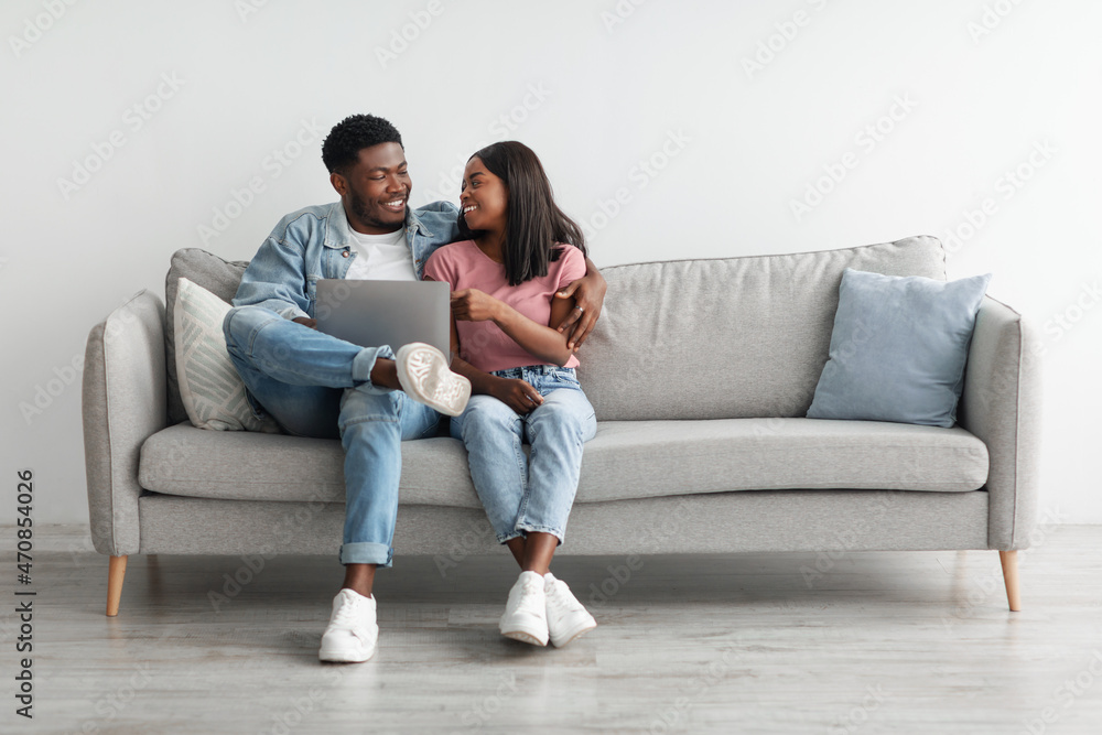 African American couple sitting on couch, using laptop African American couple sitting on couch, using laptop