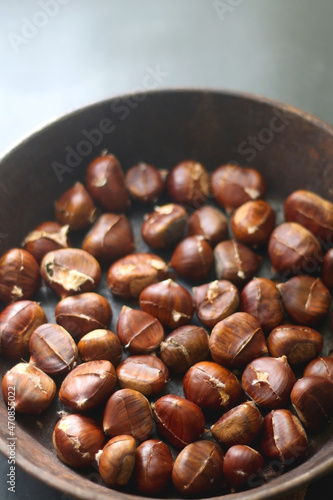 Pan filled with chestnuts on dark background. Selective focus.