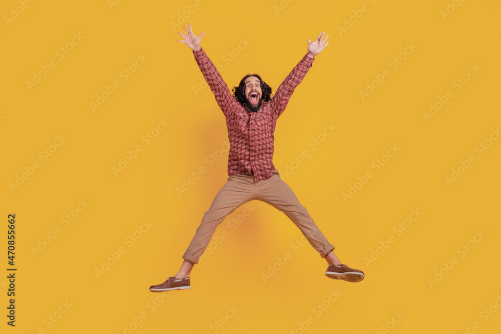 Photo of funny astonished man jump omg reaction wear checkered shirt isolated on yellow color background