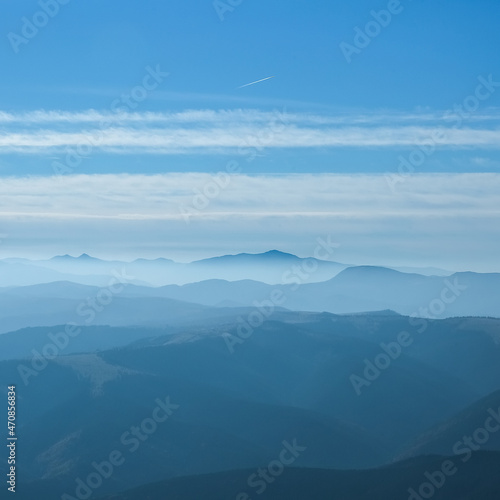 The beautiful landscape, silhouette of mountains covered with coniferous wood, cloudy blue sky after sunset