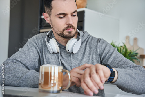 Happy caucasian male using laptop at home while looking at the watches