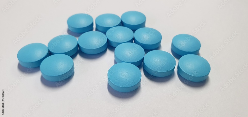 Blue tablets and vitamins without packaging on the table. Treatment pills. Useful vitamins for treatment. Blue tablets and vitamins without packaging on the table. Treatment pills. Useful vitamins for treatment.
