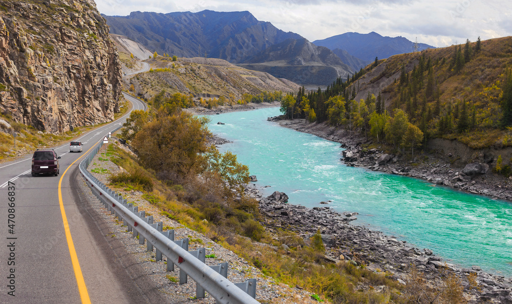 cars move along a mountain road along a mountain river and rocks. fuzzy focus cars move along a mountain road along a mountain river and rocks. fuzzy focus