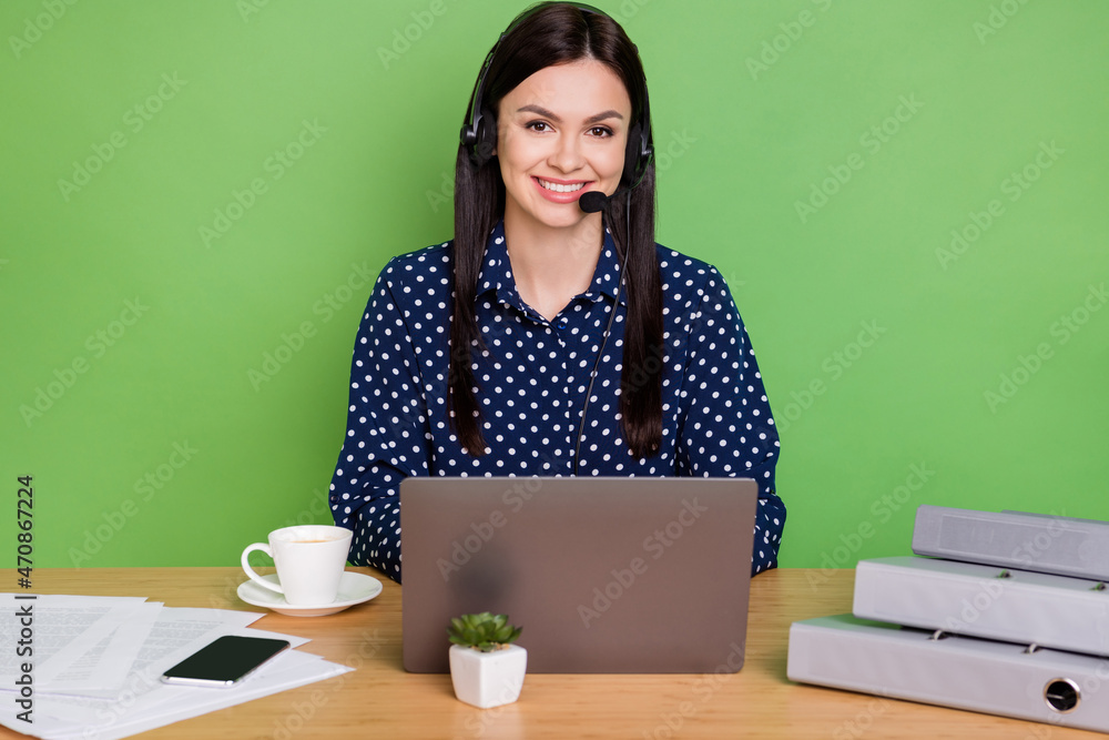 Photo of positive girl customer support service worker wear dotted shirt isolated on green color background Photo of positive girl customer support service worker wear dotted shirt isolated on green color background