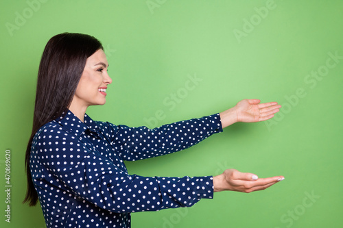 Profile side photo of happy cheerful young woman look open hands empty space isolated on green color background