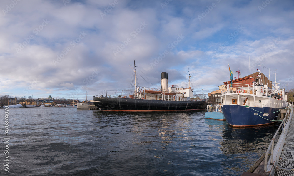 Fototapeta premium Autumn harbor view with different museum boats at a jetty in Stockholm