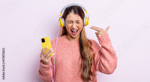 asiatic pretty woman looking unhappy and stressed, suicide gesture making gun sign. headphones and phone concept photo