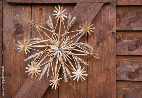 Christmas star (snowflake) made of straw on wooden wall of rural house in France.