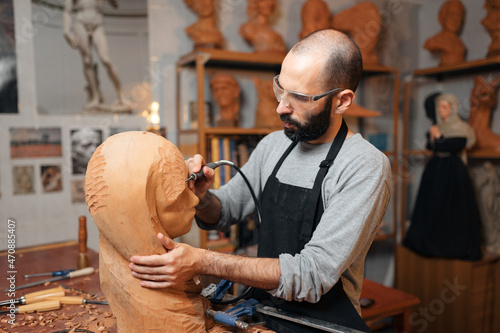 Craftsman carving wooden sculpture in workshop