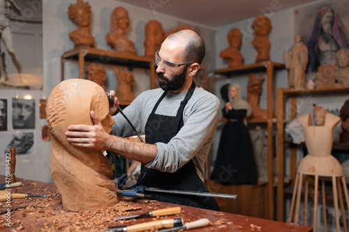 Craftsman carving wooden sculpture in workshop photo