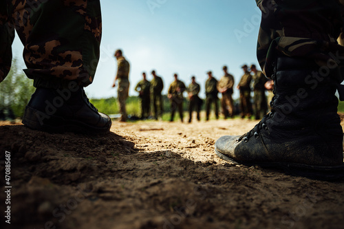 the feet of soldiers in army boots are standing on the sand. training ground before a long march photo
