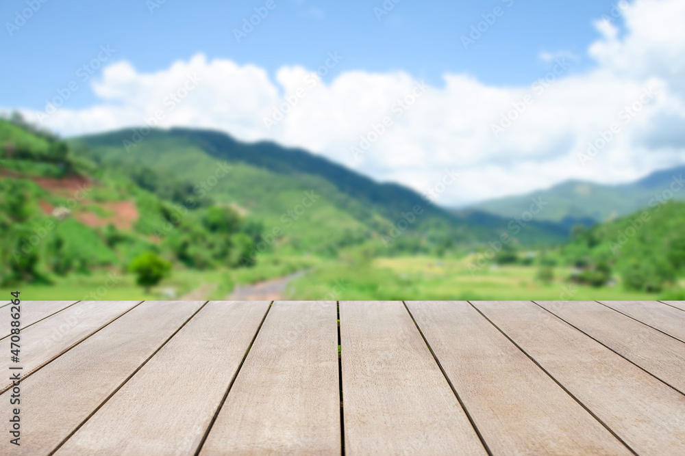 Empty old wooden top table in front of blurred beautiful mountain view, forest and cloud on blue sky at country side on clear day background. Can be used for display or montage for show your product. Empty old wooden top table in front of blurred beautiful mountain view, forest and cloud on blue sky at country side on clear day background. Can be used for display or montage for show your product.