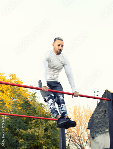 Muscular young man working out on the bar outside, street workout