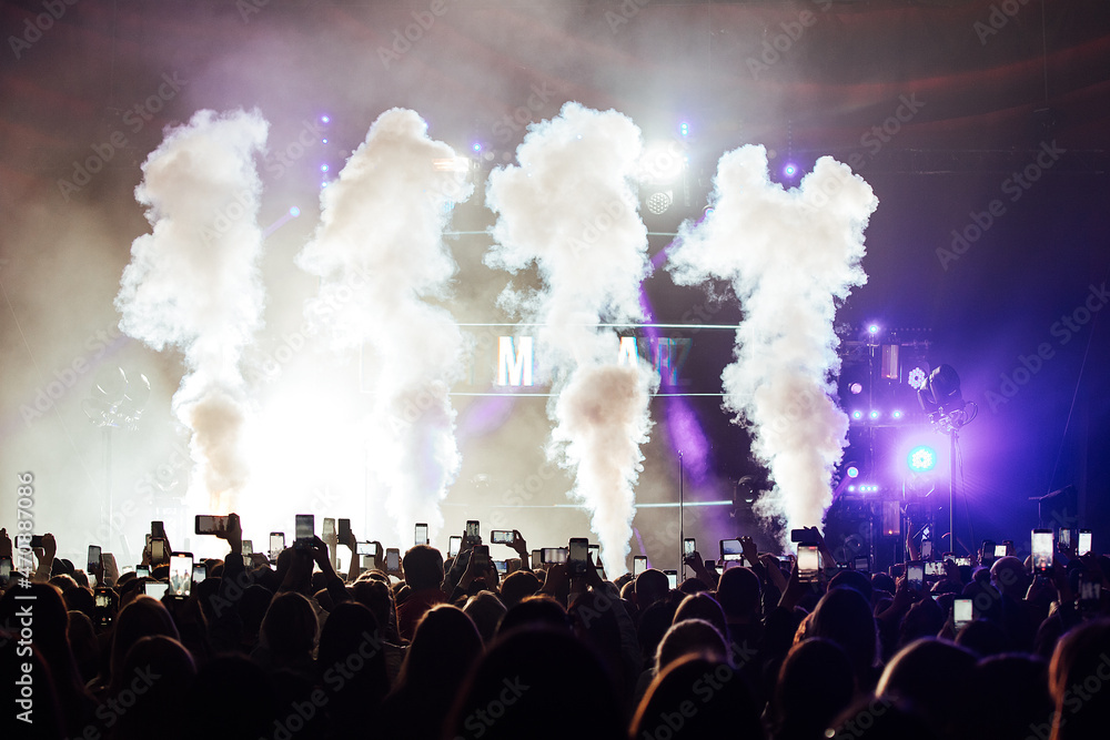a smoke machine at a concert. smoke cannons generate columns of smoke. special effects at a music concert for a crowd of spectators. dancing in the hall