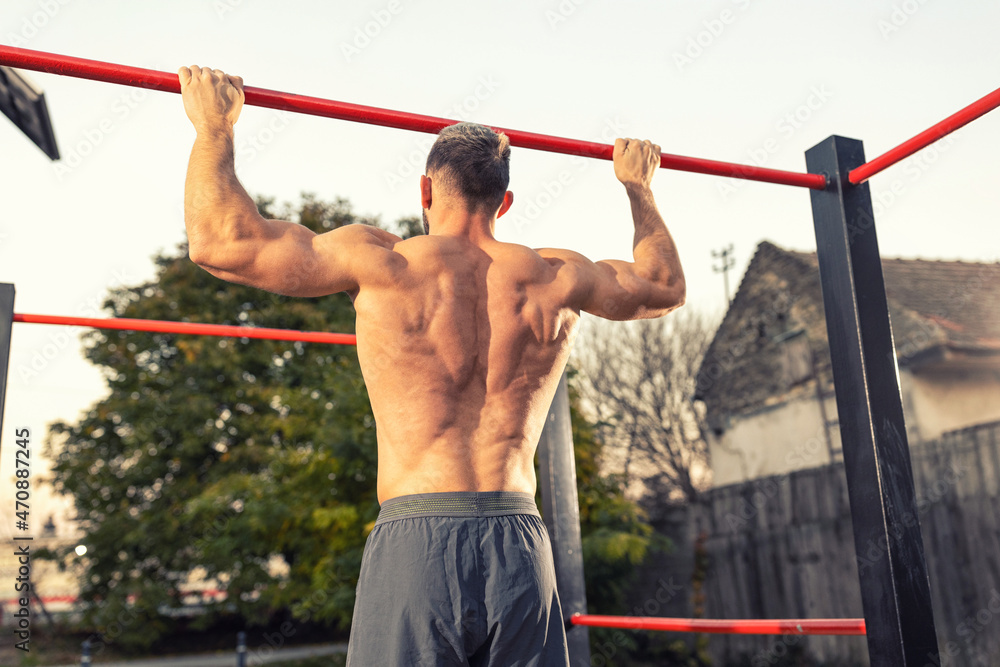 Close up of young muscular mans torso while he is doing pull ups taken from the back, close up of back muscles Close up of young muscular mans torso while he is doing pull ups taken from the back, close up of back muscles