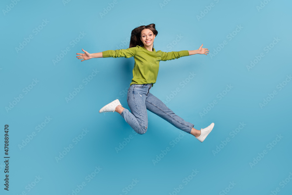 Photo of pretty cheerful lady jump hurry run open hands wear green shirt jeans footwear isolated blue color background