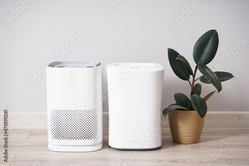 Modern humidifier and air purifier with houseplant against color background