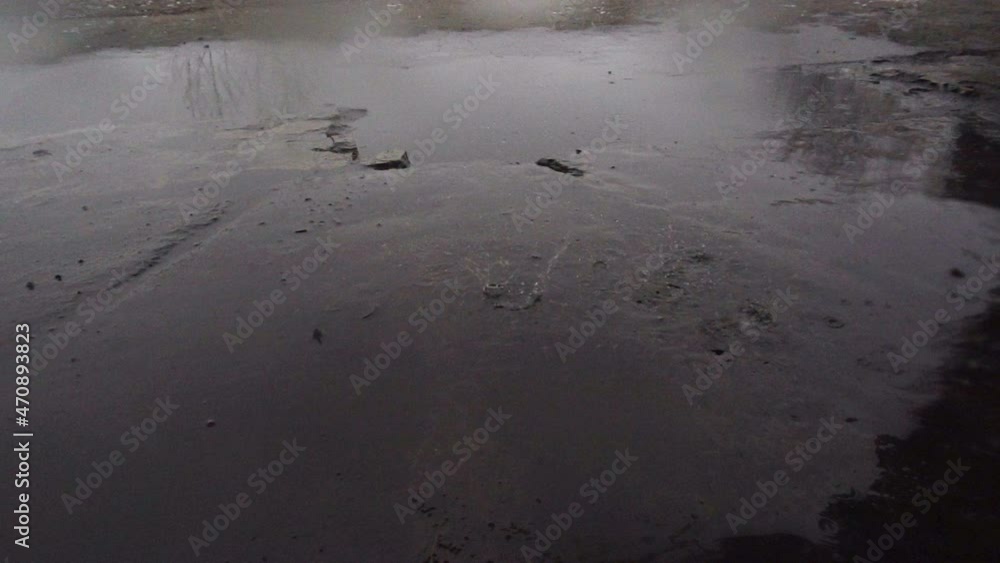 Raindrops dripping in slow motion onto the road with puddles. Raindrops dripping in slow motion onto the road with puddles.