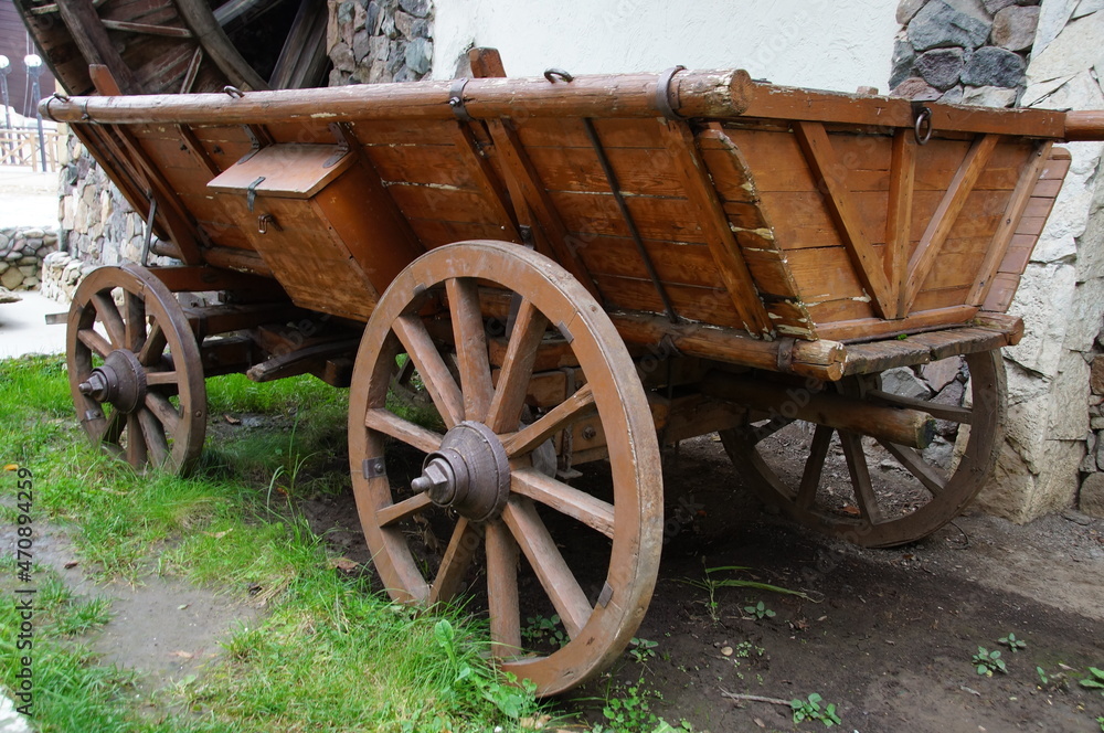 An old wooden cart near the watermill. A cart with wooden wheels. An old cart for transportation.
