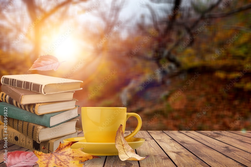 Tea cup with bright fallen leaves and books in the garden. autumn seasonal composition. Tea cup with bright fallen leaves and books in the garden. autumn seasonal composition.