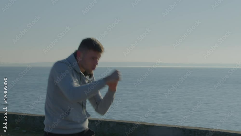 Young man practices cardio boxing, focusing on upper-body muscles, warming up in beautiful park before everyday training, healthy lifestyle, Slow motion. Young man practices cardio boxing, focusing on upper-body muscles, warming up in beautiful park before everyday training, healthy lifestyle, Slow motion.